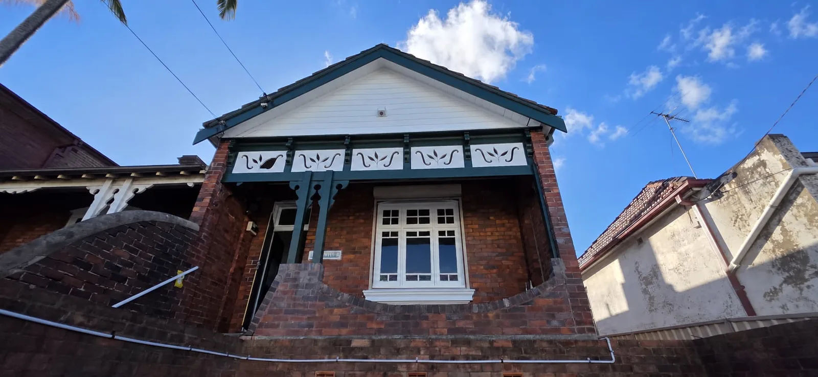 Exterior repaint, Federation brick home with deep green trims and white fretwork gable, Sydney