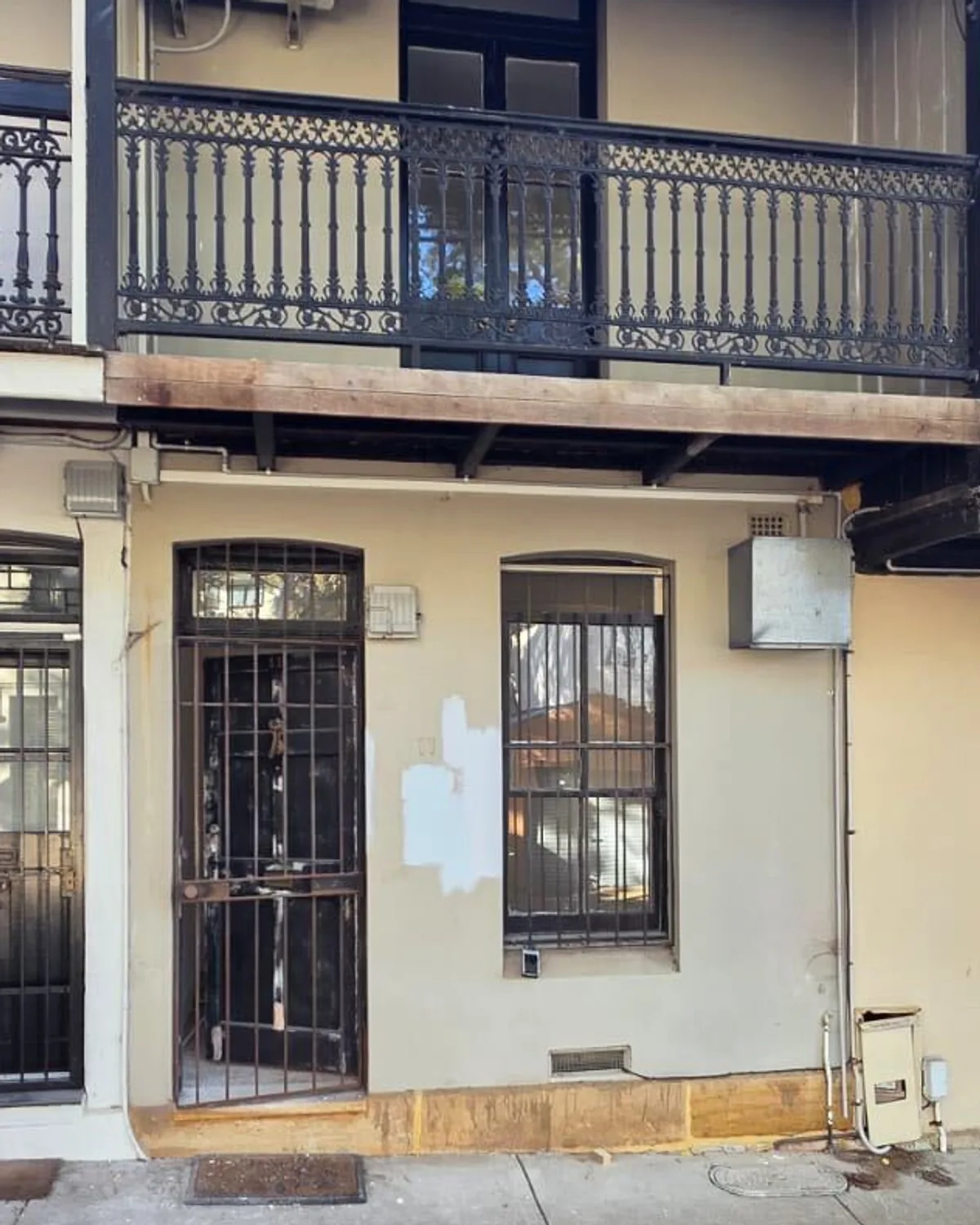 Terrace facade in tired cream render with patched walls before repainting, Sydney