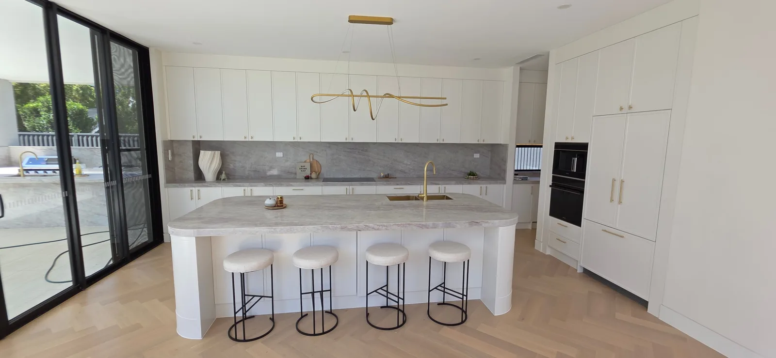 Interior repaint, white kitchen with marble island and brass pendant over herringbone oak, Sydney