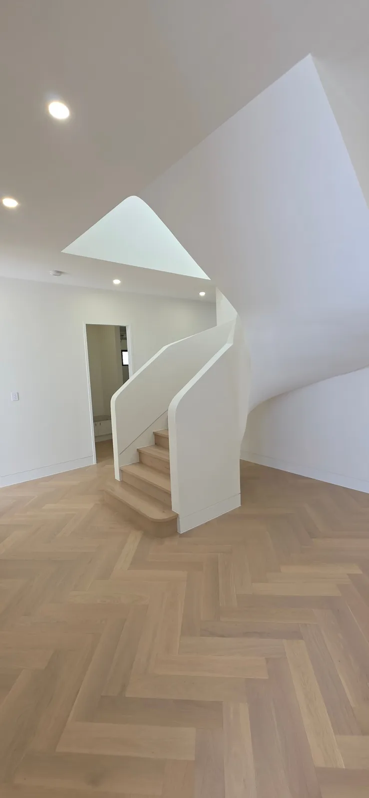 Interior repaint, living space with a curved stair over herringbone oak, Sydney