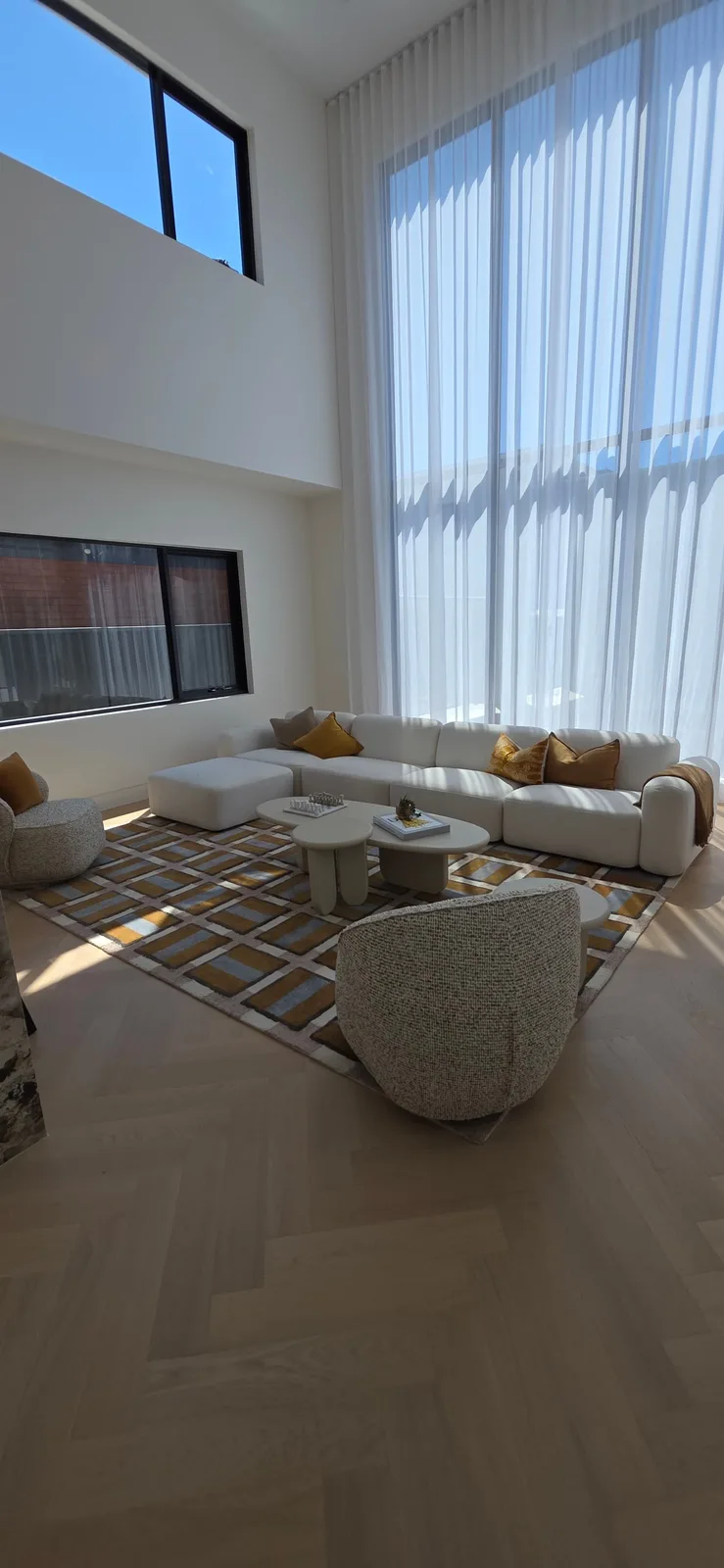 Interior repaint, double height living room with sheer curtains and white sofa, Sydney