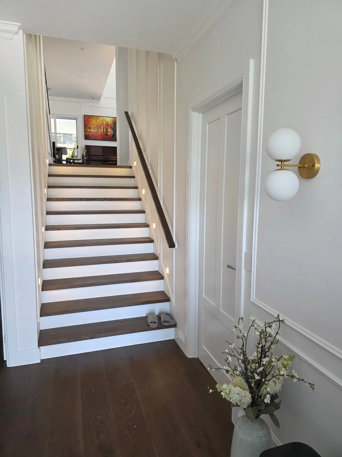 Interior repaint, panelled stair and hallway with a brass globe sconce, Sydney