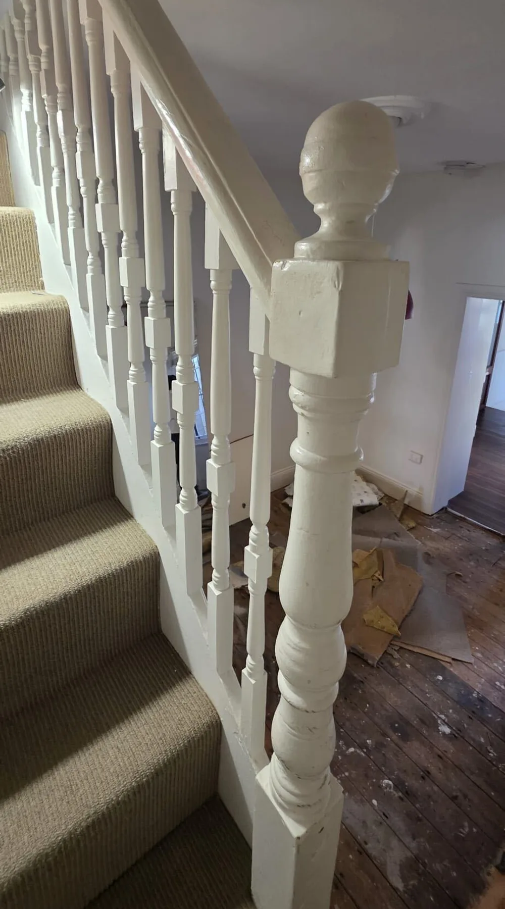 Staircase balustrade and hallway before repainting, with bare floorboards and drop sheets down, Sydney